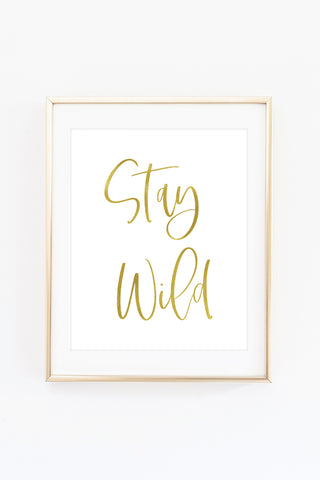 a white and gold framed poster with the words stay wild
